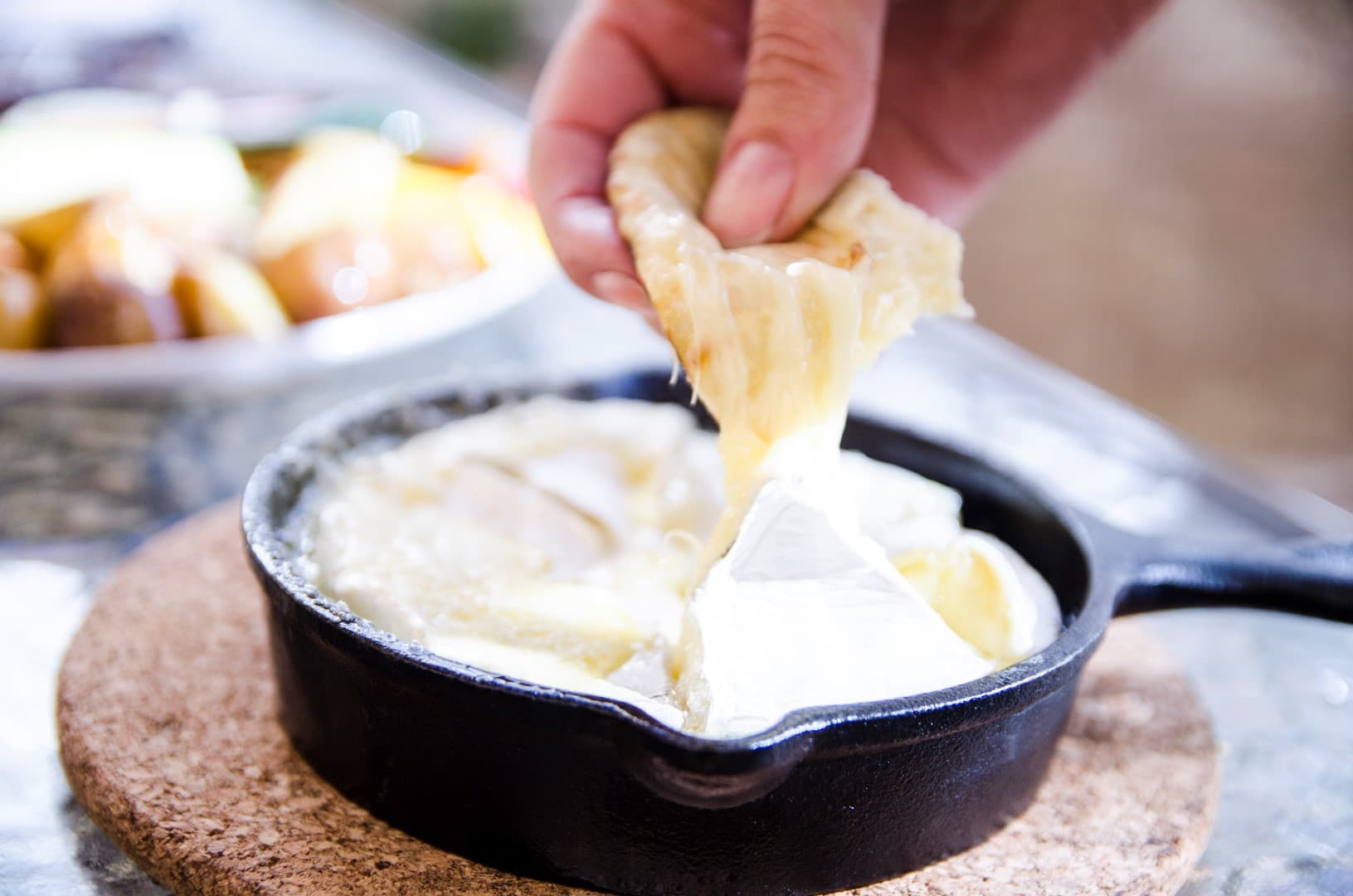 Baked brie melting in a cast-iron skillet over the fire